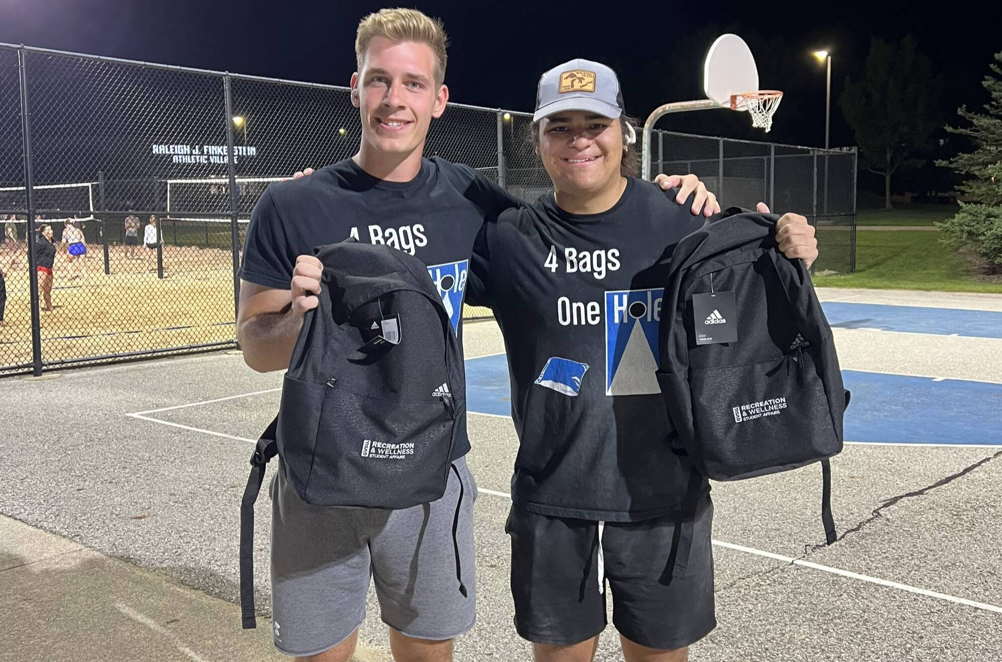 two people holding up black backpacks